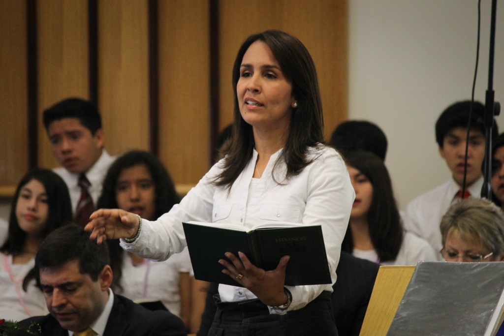 Hermana dirigiendo el himno de la congregación.