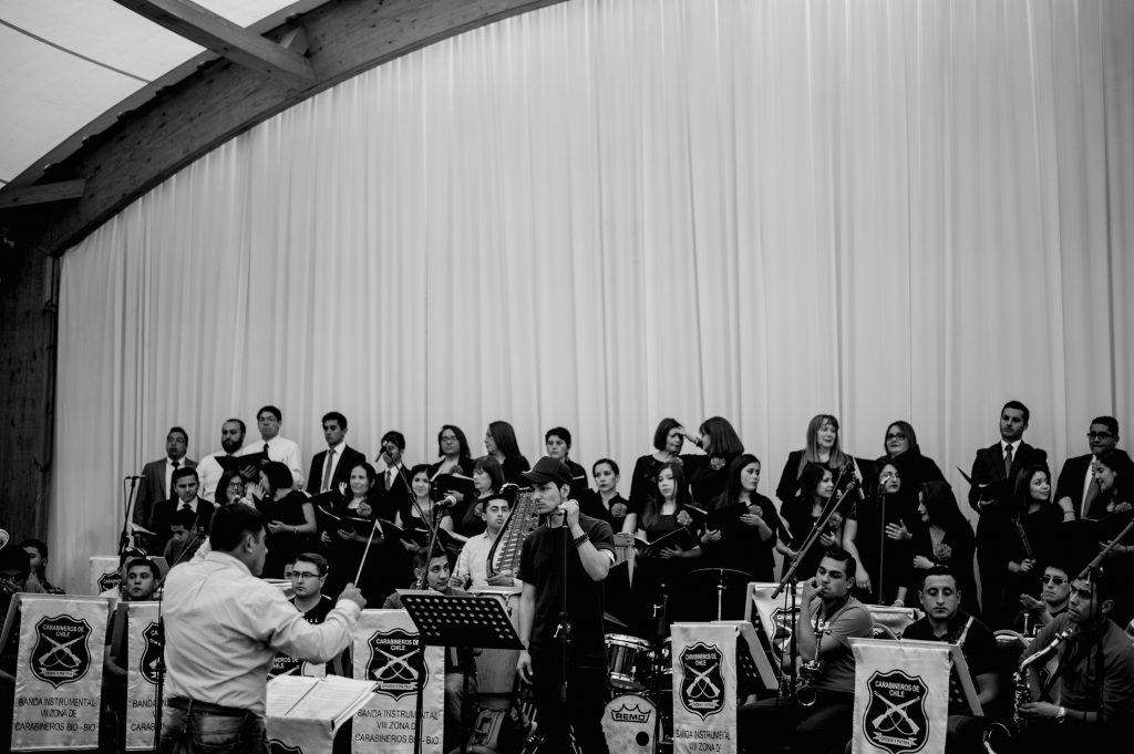 Luis Layseca junto a la Orquesta de Carabinero y al Coro de la Iglesia SUD de la Región Concepción durante el ensayo general. | Niko Serey, El Faro Mormón.